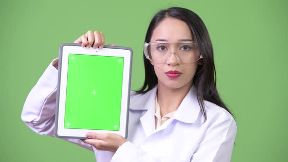Young Beautiful Asian Woman Doctor Wearing Protective Glasses and Showing Digital Tablet