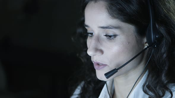 Businesswoman in Headset Talking in Dark Office