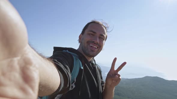 The traveler blogger makes a selfie on the mountain against the background of the sea. 