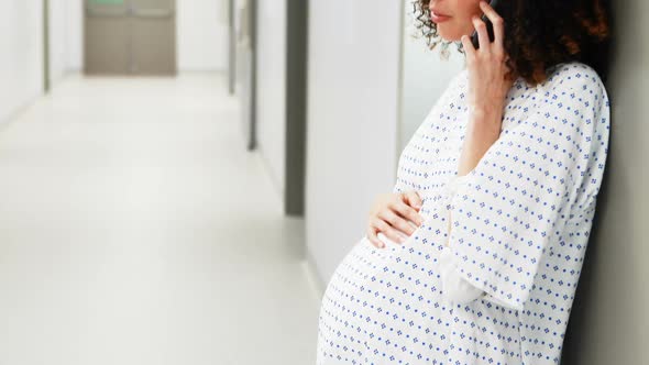 Pregnant woman talking on mobile phone in corridor