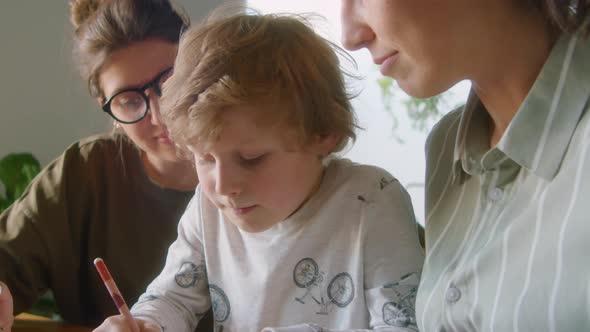 Child Studying at Home with Help of Lesbian Parents