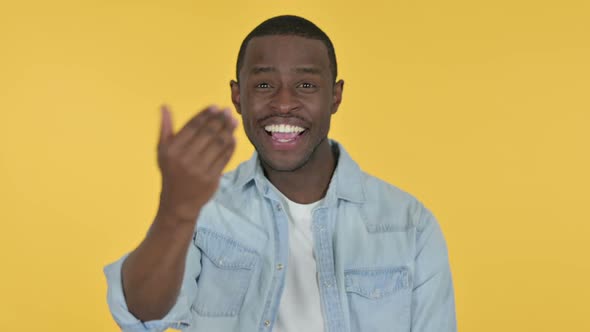 Young African Man Pointing and Inviting Yellow Background