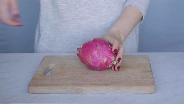 Young Woman Cutting Dragon Fruit Into Two Halves