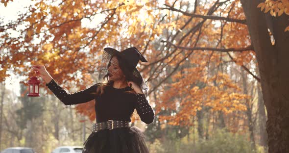 Attractive Woman in a Special Dress and Hat Looks Like a Witch in the Autumn Forest