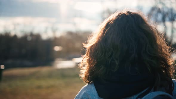 Back Shot of a Young Woman with Curly Hair Enjoying the Sun