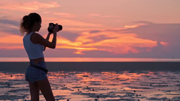 Woman Taking Pictures of the Sunset on the Beach