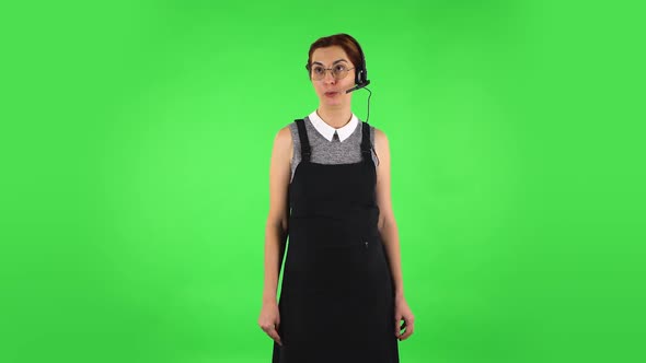Funny Girl in Round Glasses Is Talking on Headphones, Call Center. Green Screen