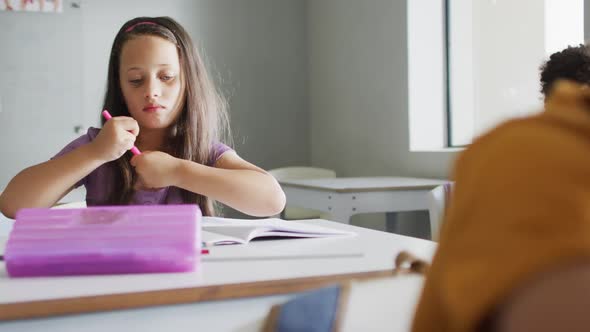 Video of caucasian girl sitting at desk in classsroom