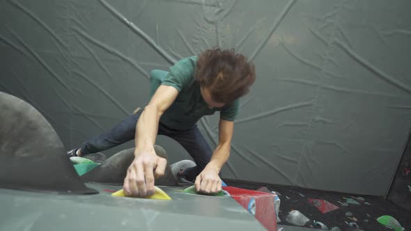 Man Climbs the Wall Training on a Climbing Wall Practicing Rockclimbing Mountaineer Training