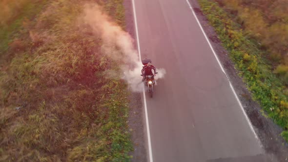 Aerial Top View: Motorcyclist Revs and Makes Burnout Tire with Smoke on Asphalt Road