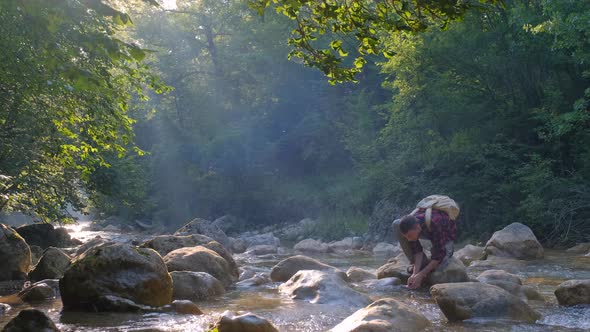 Young Man Relaxing on the Rock By River in the Forest