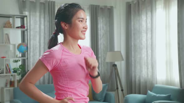 Side View Of Asian Woman Running On A Treadmill At Home