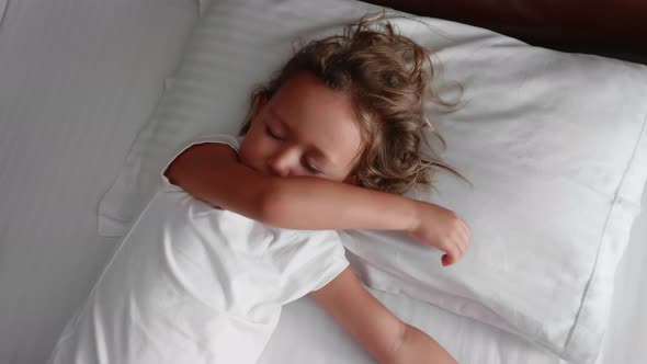 Little Cute Girl Is Waking Up and Stretching in Bed at the Morning.