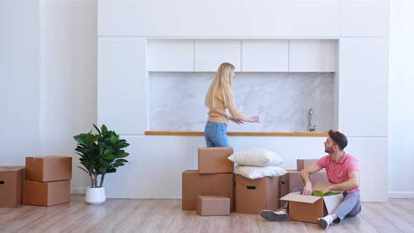 Young woman blonde with long loose hair helps bearded man unpack brown cardboard