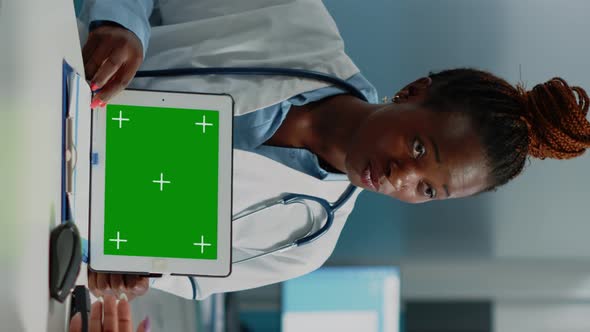 Vertical Video Black Doctor Showing Tablet with Horizontal Green Screen to Patient