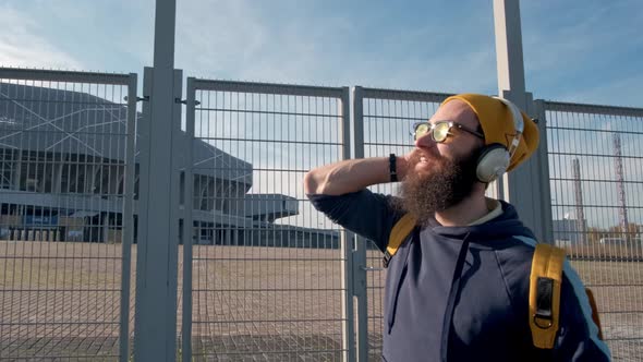 Portrait of a Stylish Bearded Man in Yellow Clothes Enjoying Music with Headphones on the Blue Sky