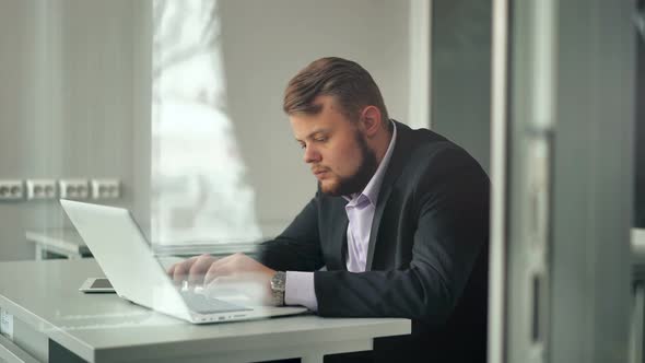 Young Businessman Working in Office Sitting at Desk Looking at Laptop Computer Screen