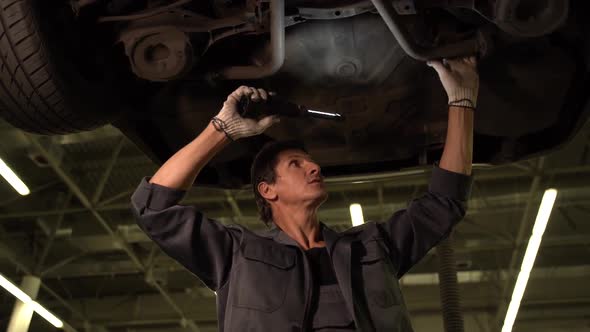 Adult professional caucasian car mechanic adjusting tension in vehicle suspension element.