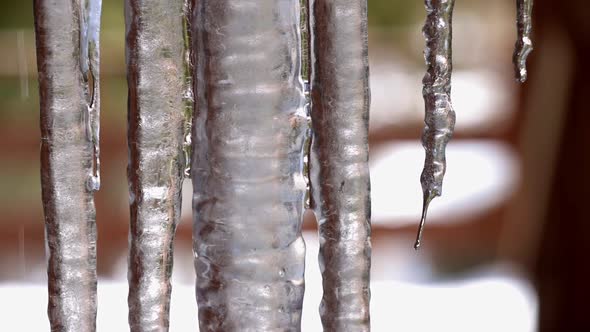 Close up of a group of hanging icicles on the deck of a home with water melting and running down the