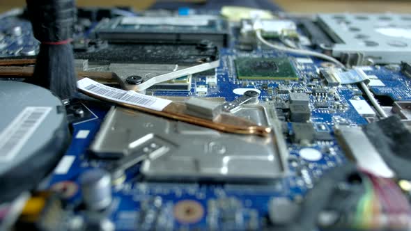 The serviceman cleans the interior of the laptop with dust and other dirt.