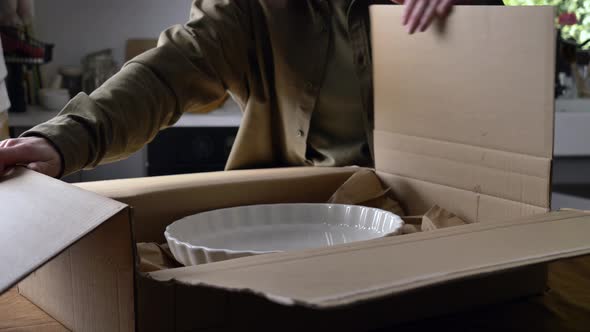 woman unpacking a box with dish in the kitchen at home