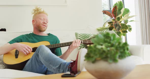 Albino african american man with dreadlocks playing guitars and singing