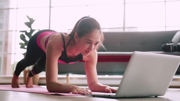 Asian girl is practicing online fitness from home.