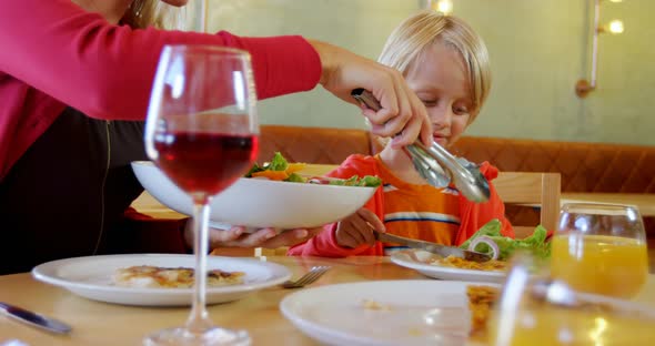 Mother serving salad to her son in restaurant 4k