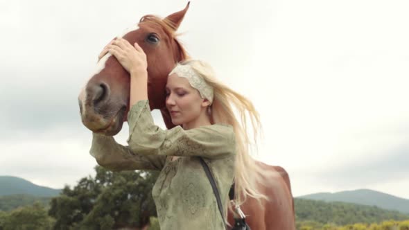 Blonde Young Woman Smiles Strokes and Hugs Brown Horse Outdoor and Look at Camera Gimbal Steadicam