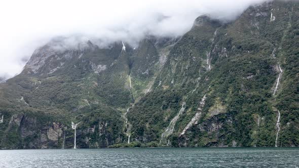 Panning shot of low hanging clouds at Milford Sound Fiordland. Natural waterfalls at Milford sound N