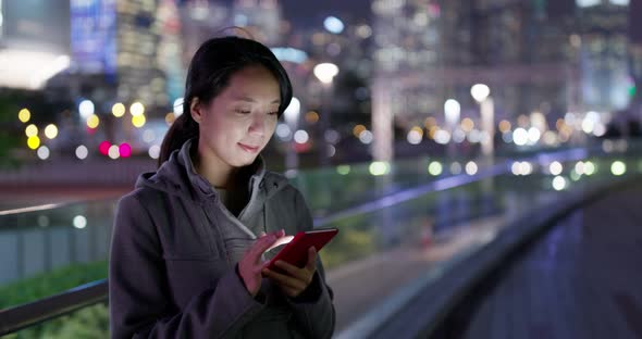 Woman look at mobile phone in city at night