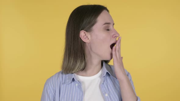 Tired Young Woman Yawning on Yellow Background