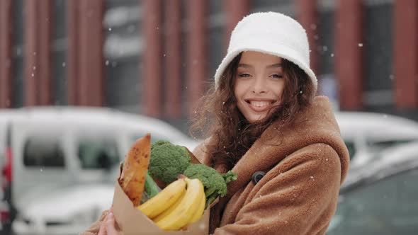 A Woman is Standing Near a Supermarket and Looking at the Camera