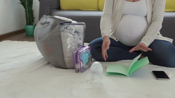 Cute Pregnant Woman Writing Packing List For Maternity Hospital Notebook Prepares Bag
