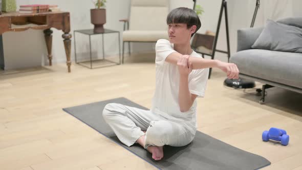 Asian Man Doing Stretches on Yoga Mat at Home