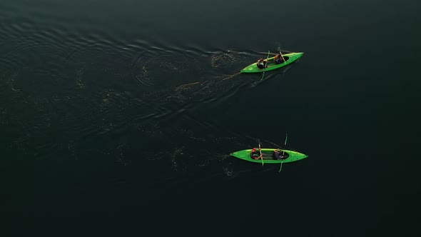 Two Kayaks with Four Oarsmen Float on Water Without Waves