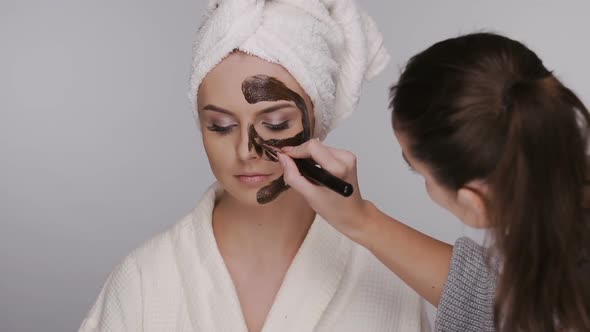 Woman Applying Brown Cream on Girl's Face in Bath Costume