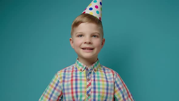 Young Boy Wearing Birthday Hat Congratulating Talking to Camera on Blue Background