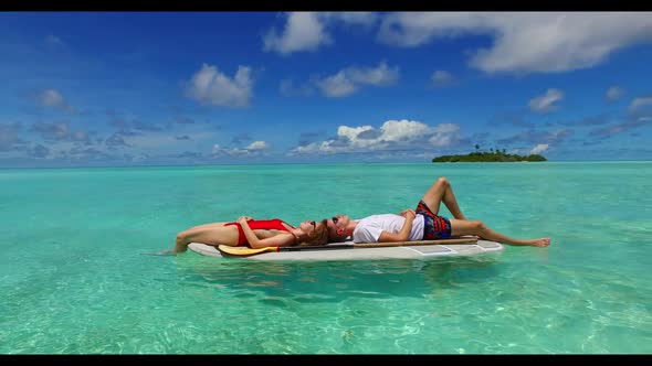 Two people posing on exotic shore beach voyage by blue green sea and white sand background of the Ma