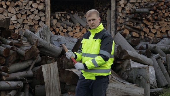 Lumberjack in Reflective Jacket. Man Woodcutter Hold Small Axe. Sawn Logs, Firewood Background