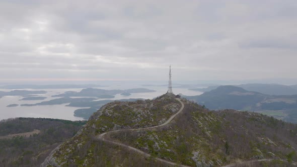 Winding Road Up A Mountain With Phone Mast Tower Overlooking A Misty Lake. - aerial