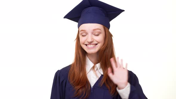 Happy Smiling Redhead Graduate Caucasian Girl in Blue Academic Dress Waving Her Hand