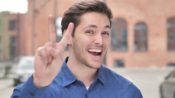 Victory Sign by Positive Young Man Standing Outdoor