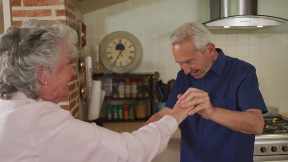 Senior caucasian couple dancing in kitchen in slow motion