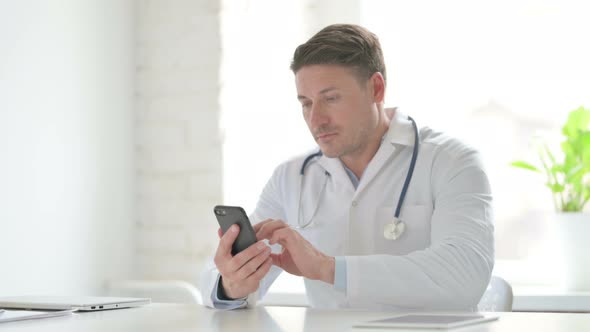 Male Doctor Browsing Internet on Smartphone in Office