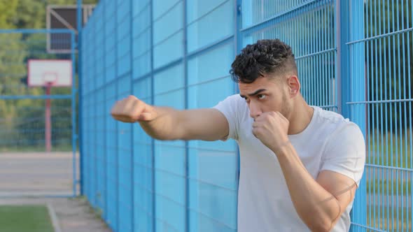 Serious Focused Young Arabic Hispanic Male Athlete Boxer Waving Hands with Clenched Fists Showing