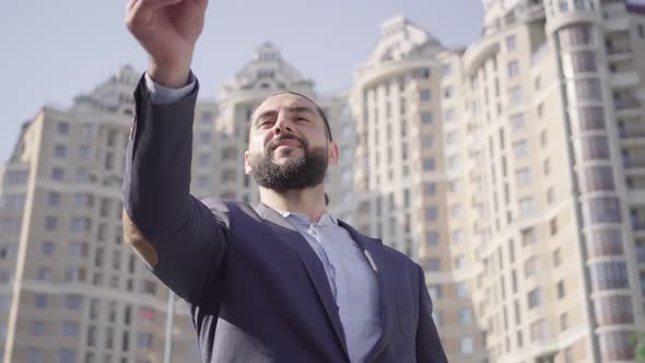 Positive Successful Middle Eastern Businessman Throwing and Catching Key and Making Victory Gestures