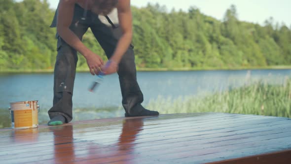 Young man painted roof of wooden boat cabin with bondex exterior protective paint.