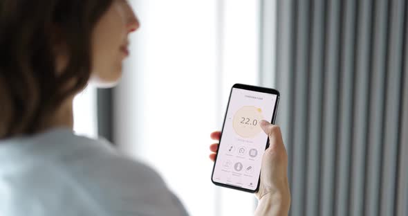 Woman Adjusting Room Temperature with a Smart Phone