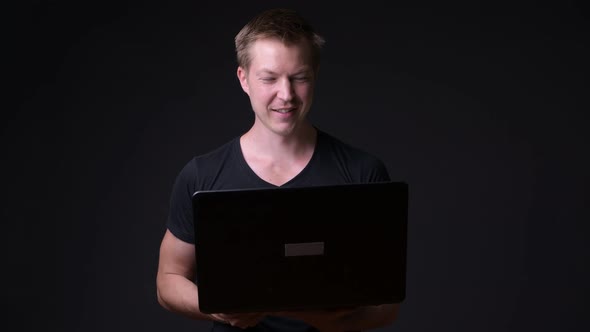 Young Handsome Man with Laptop Against Black Background